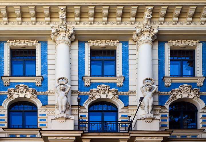 Façade of Strēlnieku iela 4a: glazed brick between columns, with sculpted figures beside the windows.